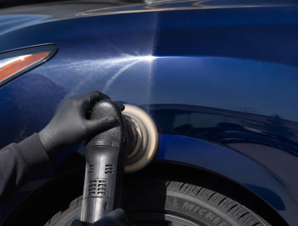 Dual action polisher removing swirl marks from dark blue car paint